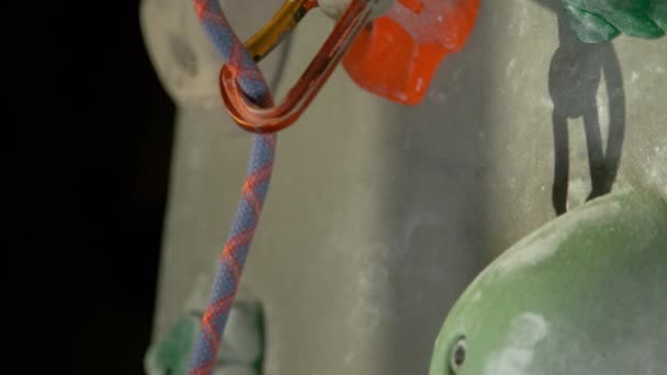 MACRO: Färgglada belay rep glider ut ur en karbinhake och faller längs väggen — Stockvideo