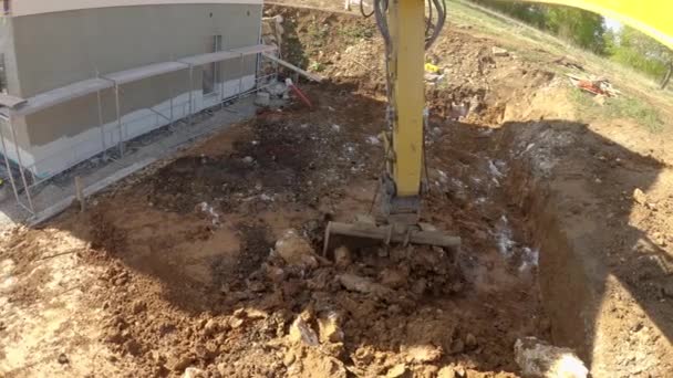 POV: Navegando una excavadora en un sitio de construcción, excavando tierra cerca de una casa — Vídeo de stock