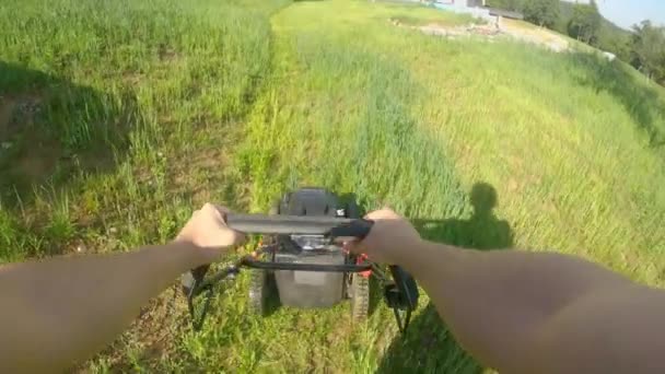 POV: Een gemotoriseerde grasmaaier langs een overwoekerde achtertuin duwen in de lente. — Stockvideo