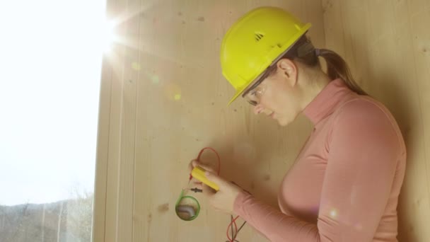 ПОРТРАЙТ: женщина-электрик улыбается после тестирования тока в проводах. — стоковое видео