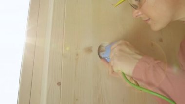Genç beyaz kadın ahşap duvara plastik bir soket takıyor..
