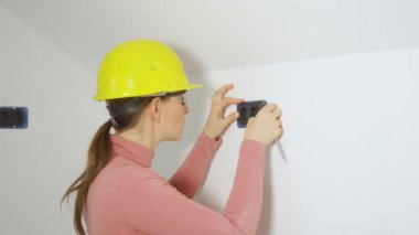 Kadın müteahhit, prizleri duvara yerleştirdikten sonra kameraya bakar.