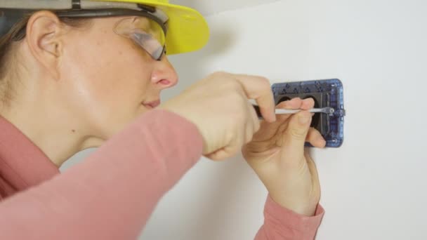 CERRAR: Mujer atornillando tornillos en la pared durante la instalación de tomas de corriente — Vídeo de stock