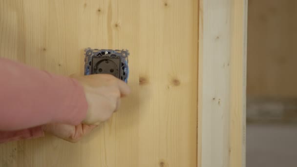 FERMER : Une femme méconnaissable installe une prise électrique sur un mur en bois. — Video