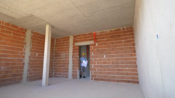 LOW MOTION: Jovem supervisor de construção olha em torno da sala inacabada . — Vídeo de Stock