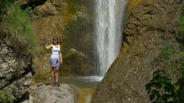 COPY SPACE: Jovem mulher tira selfies ao lado de uma bela cachoeira na Eslovênia . — Vídeo de Stock