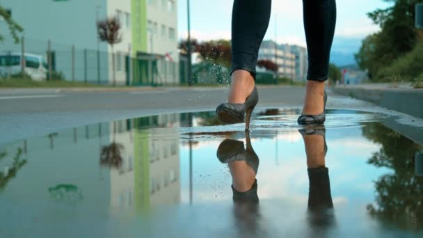 近身：穿着高跟鞋的难以辨认的年轻女子走进了一个玻璃状的水坑. — 图库视频影像