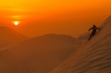 SILHOUETTE: Spectacular shot of pro skier riding off trail on a sunny evening. clipart