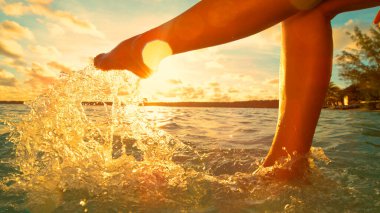 Tanınmayan kadın ferahlatıcı okyanus suyunu tekmelerken eğleniyor..