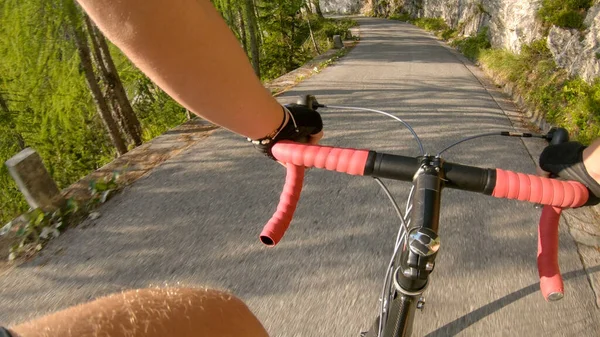 POV: Pedaleando una bicicleta de carretera por una empinada carretera asfaltada en las soleadas montañas . —  Fotos de Stock