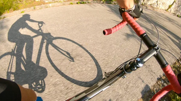 POV: Αγνώριστο ταιριάζει άνθρωπος πεντάλ το ποδήλατο δρόμο του κάτω από μια απότομη άσφαλτο δρόμο. — Φωτογραφία Αρχείου