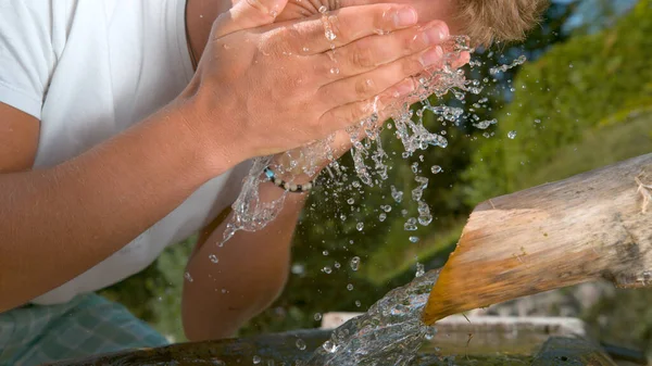 閉じる:未知の若い男は顔を洗うことによって彼のトレッキング中にリフレッシュします。. — ストック写真