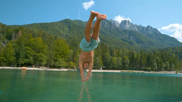 FERMER : Un touriste masculin actif saute la tête la première dans le lac froid rafraîchissant. — Photo