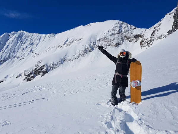 Femme snowboarder célèbre atteindre le sommet de la montagne par une journée d'hiver ensoleillée. — Photo
