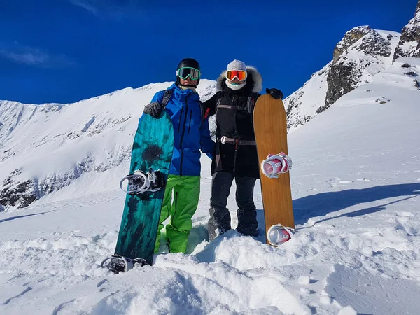 Actief jong stel poseert met hun snowboards hoog in de prachtige Rockies. — Stockfoto