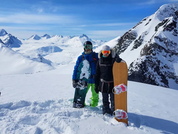 Gelukkig jong snowboarder paar poseert in spectaculaire bergen op een zonnige dag. — Stockfoto