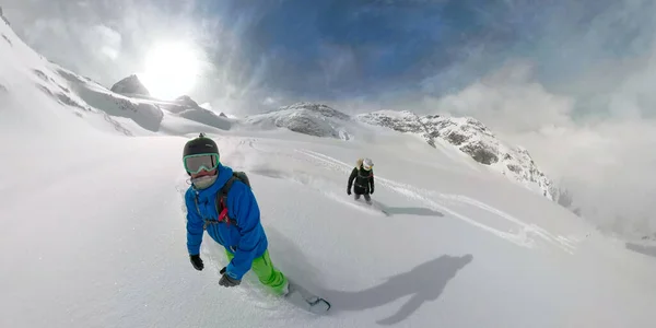 360 VR: Turistas activos femeninos y masculinos haciendo snowboard fuera de pista en las Rocosas . —  Fotos de Stock