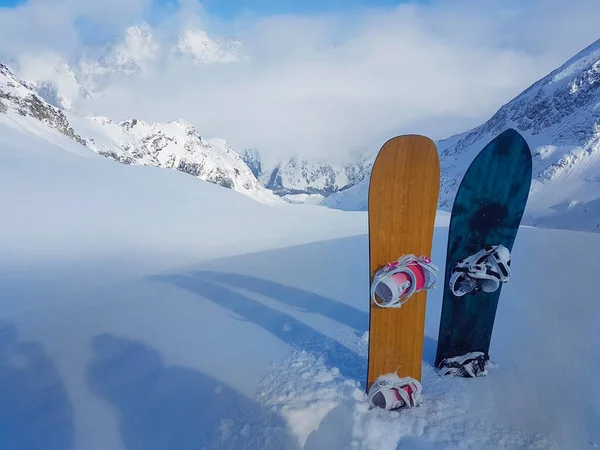 Twee snowboards zitten vast in de poedersneeuw op de top van de berg. — Stockfoto