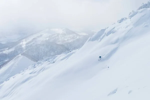 AERIAL: Ο άνθρωπος τεμαχίζει το χιονισμένο ορεινό έδαφος, ενώ σε ένα διασκεδαστικό ταξίδι σκι στην Ιαπωνία. — Φωτογραφία Αρχείου