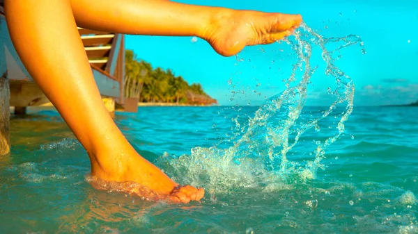 CERRAR Chica despreocupada de vacaciones sentado en el muelle y salpicaduras de agua del océano — Foto de Stock