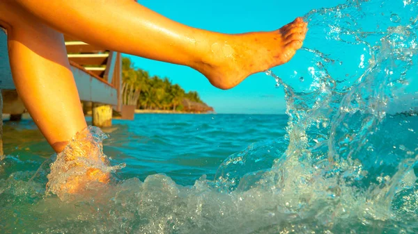 CLOSE UP: Verspielte Touristin tritt mit den Füßen ins erfrischende Meerwasser. — Stockfoto