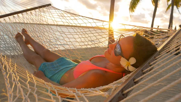 LENS FLARE: arany napsugarak ragyog a nyugodt nő lengő függőágy. — Stock Fotó