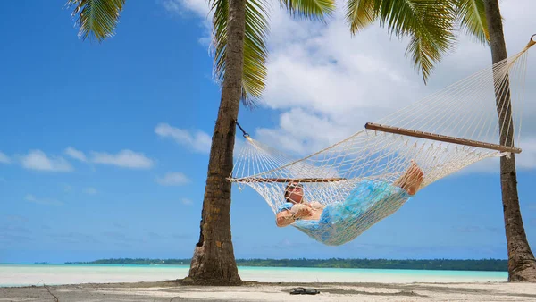 ANGOLO BASSO: Donna rilassata dorme sulla spiaggia tropicale su un'amaca di corda ondeggiante — Foto Stock