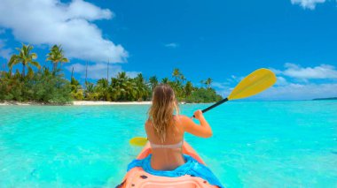 Gezgin kız, çarpıcı beyaz kum kıyısına doğru kürek çekiyor..