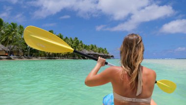 Tanınmayan bir kadın su altındaki villalara doğru kanosuyla kürek çekiyor..