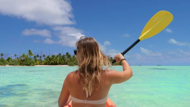Kaygısız genç kadın kayak yapıyor ve yemyeşil tropik adayı keşfediyor..