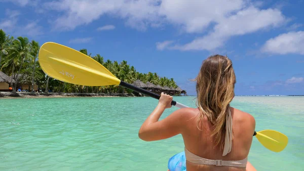 CERRAR: Mujer irreconocible remando su kayak hacia villas sobre el agua. —  Fotos de Stock