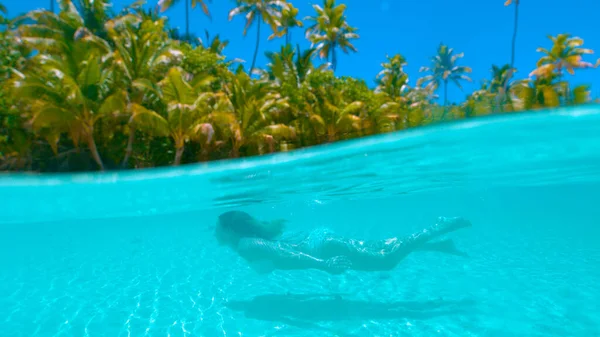 HALF HALF: Mujer joven nadando bajo el agua durante las vacaciones en la isla exótica . —  Fotos de Stock