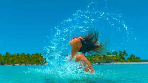 Bezárás: boldog turista lány fröccsenő a tengervíz vele hosszú barna haj. — Stock Fotó