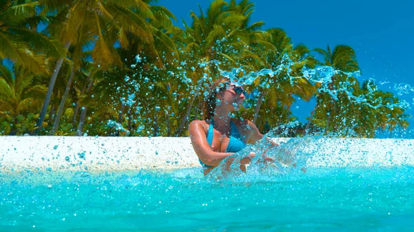 ZAMKNIJ: Uśmiechnięta kobieta na wakacjach rozbryzgująca krystalicznie czystą wodę oceanu. — Zdjęcie stockowe