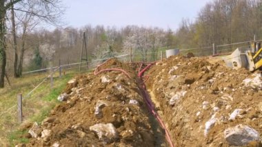 Çevrilmiş plastik telekomünikasyon boruları yeşil tepeden yukarı çıkıyor..