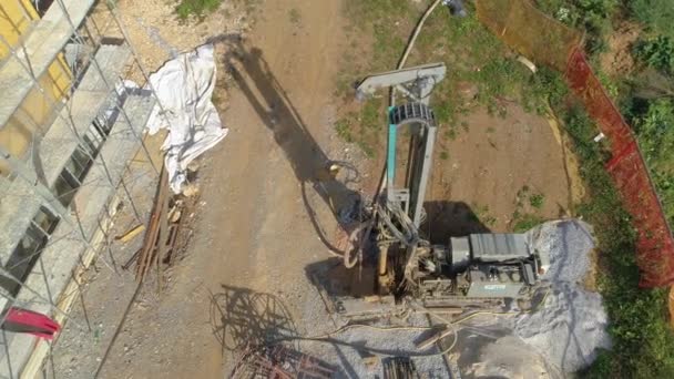 AERIAL: Voando acima de uma máquina enterrando um buraco no chão para uma bomba de calor . — Vídeo de Stock