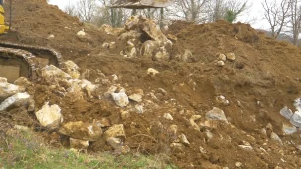 FERMER : Bras jaune de la pelle s'étend et la pelle creuse la saleté et les roches. — Video