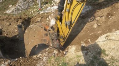 Kazı kolu, yol çalışması sırasında toprak ve kayalarla dolu kovayı topluyor.