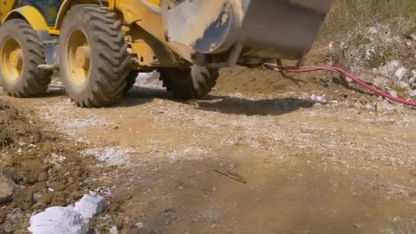 CERRAR: La excavadora amarilla grande conduce a lo largo de un camino sin pavimentar en el campo. — Vídeo de stock