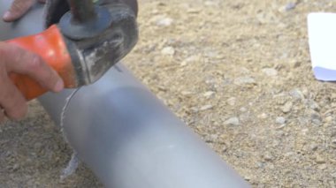Tanınmayan tesisatçı pvc kanalizasyon borusunu kesmek için bir açı öğütücü kullanıyor..