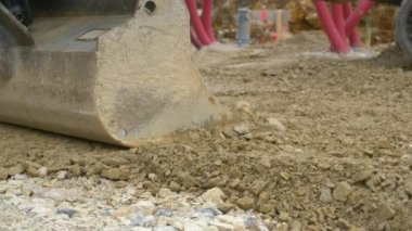 Islak kayaları ve toprağı dümdüz eden metal kürek kovasının detaylı görüntüsü..