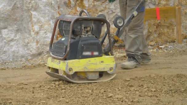 CERRAR UP El hombre utiliza la máquina de nivelación manual para preparar el terreno para el vertido de mortero — Vídeos de Stock