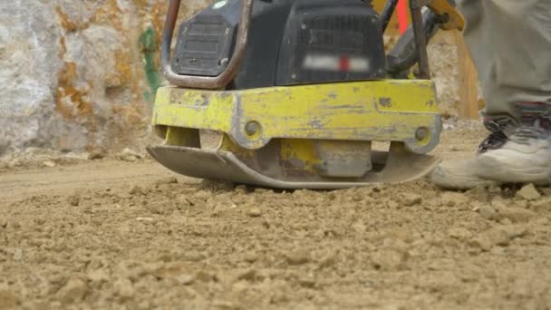 CLOSE UP: Arbetaren använder en nivelleringsmaskin för att förbereda marken för betonggjutning — Stockvideo