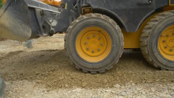 CERRAR: La excavadora amarilla grande raspa su cubo a lo largo de una capa de rocas húmedas. — Vídeo de stock