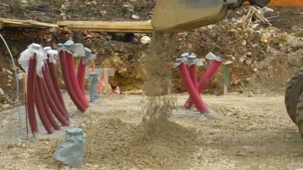 CLOSE UP: Bulldozer dumpar en hink full av stenar innan betongplattan häller. — Stockvideo