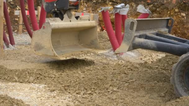 CHIUSURA: secchio pala escavatore livella la ghiaia bagnata in un cantiere. — Video Stock