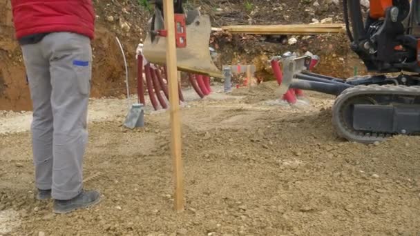 Nerozpoznatelný dělník stojí vedle vrtání štěrku na zem. — Stock video