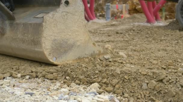 CERRAR: Captura detallada de un cubo de pala de metal nivelando rocas húmedas y tierra. — Vídeo de stock