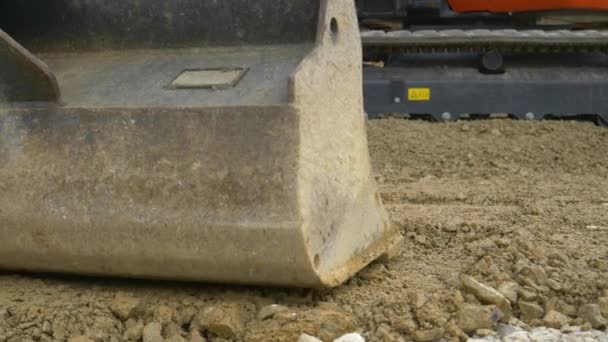 CLOSE UP: Bulldozer-Fahrer nivelliert mit einer großen Schaufel eine Schicht groben nassen Kies — Stockvideo