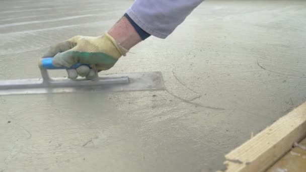 Tanımlanamayan işçi, büyük taze beton levhayı bir spatulayla dümdüz ediyor. — Stok video